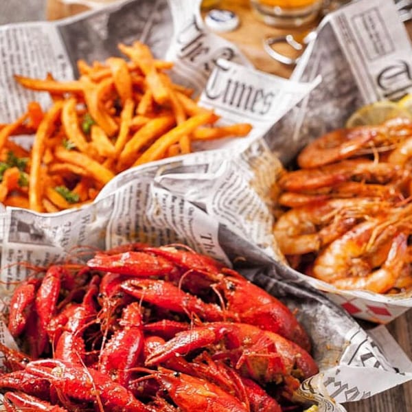 Three baskets of seafood and fries, including crawfish, shrimp, and sweet potato fries.